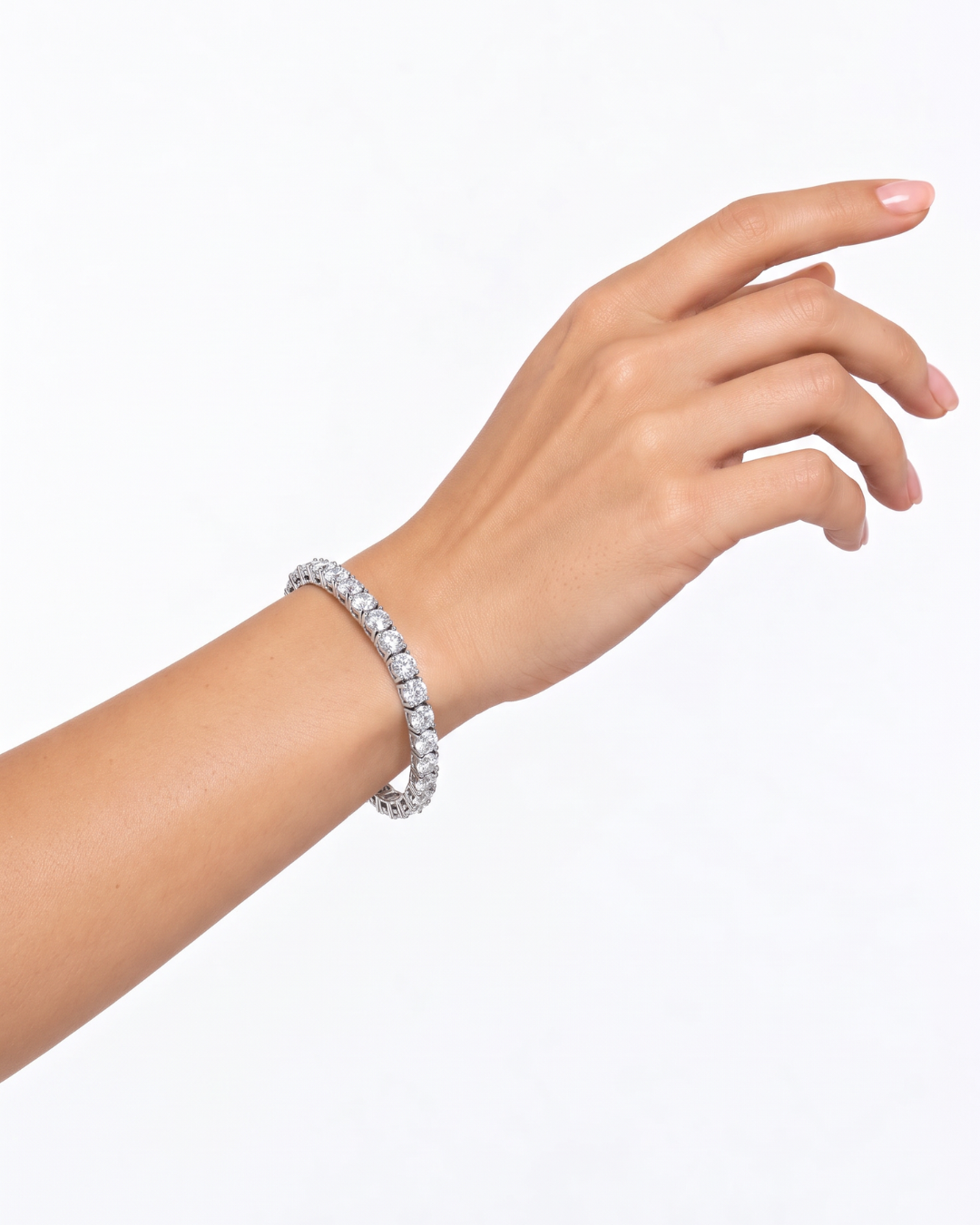 A close-up of a woman's hand and wrist wearing a sparkling diamond tennis bracelet against a clean white background.