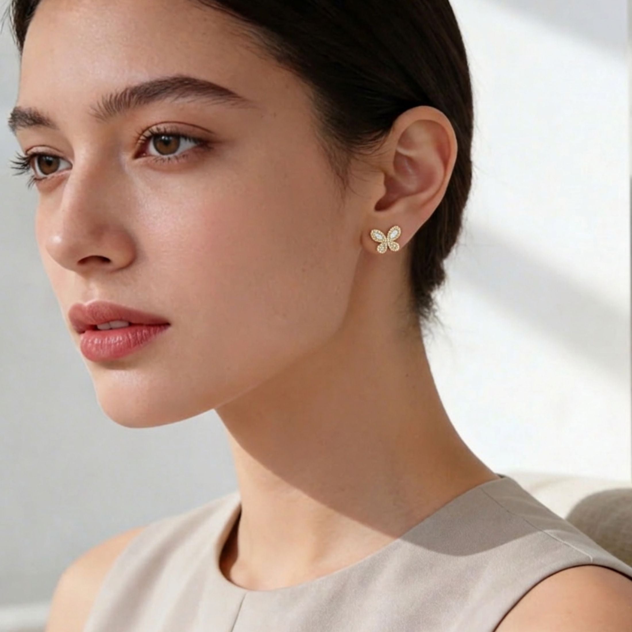 Yellow gold baguette butterfly stud earrings worn on ear showing sparkle and fit
