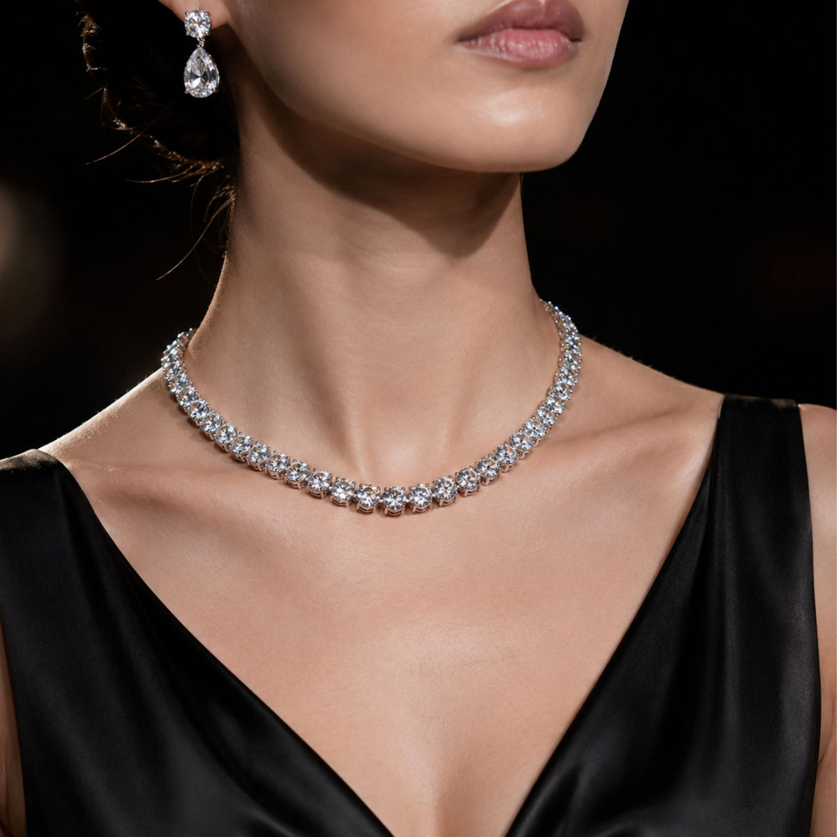 Platinum diamond rivière necklace on model in black satin V-neck dress highlighting formal wear brilliance