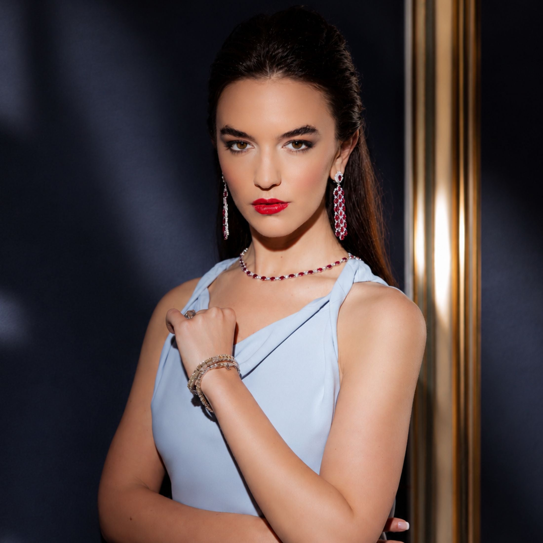 Woman wearing Leviev crimson ruby diamond dangle earrings with matching necklace