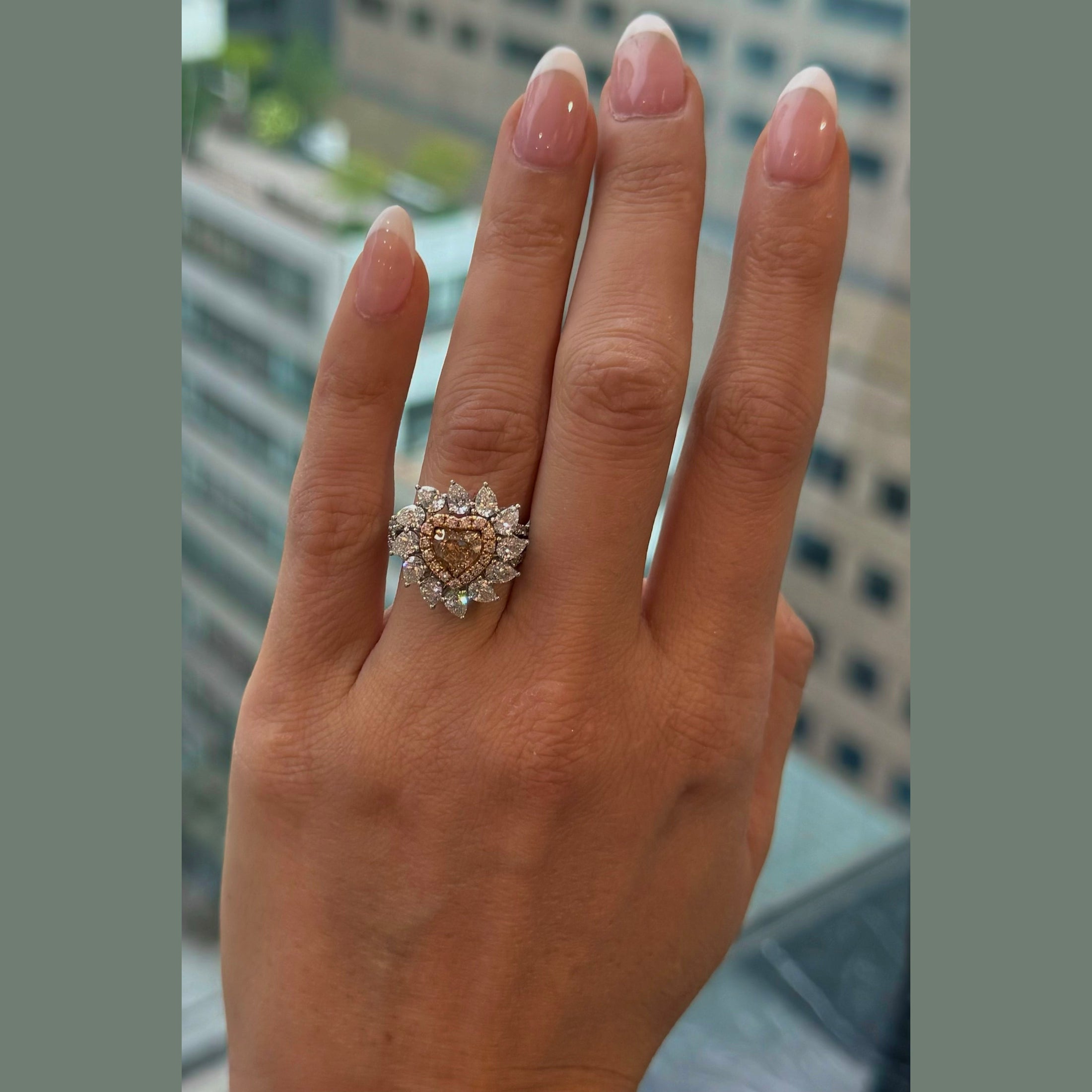 Heart shape cut fancy brown orange diamond ring on hand with white gold floral halo