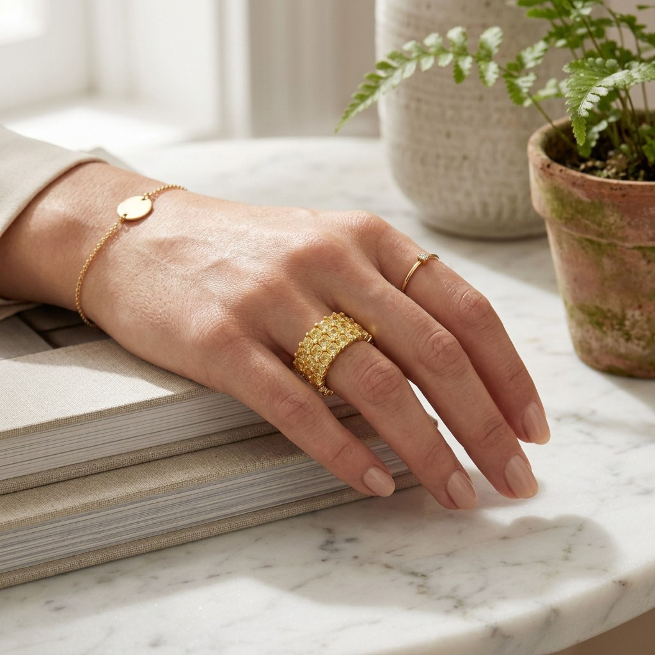 Woman wearing wide Leviev yellow gold eternity band with Asscher-cut stones on marble