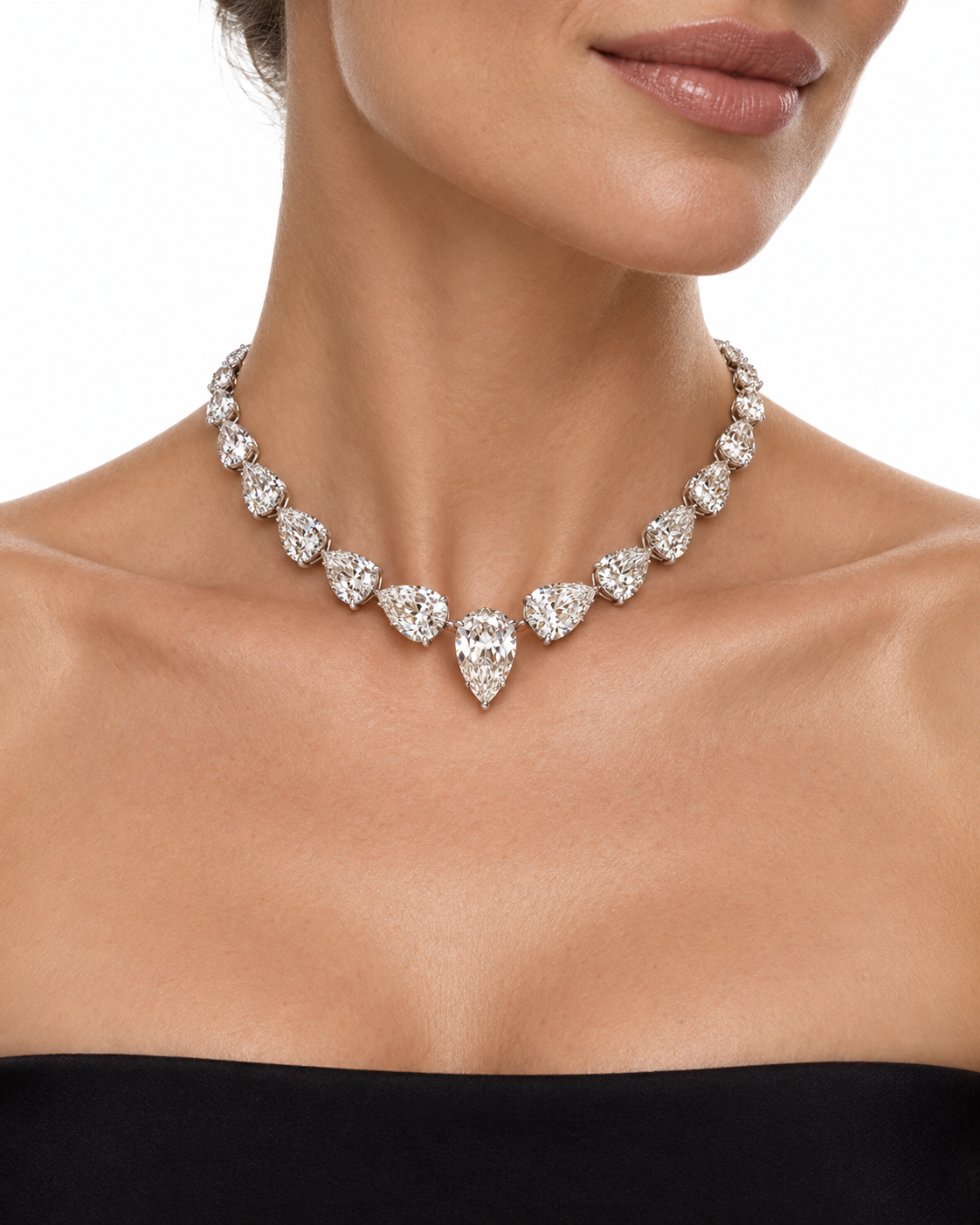 A close-up of a model wearing a pear-shaped diamond chocker in a platinum setting, paired with a black strapless top against a white background.