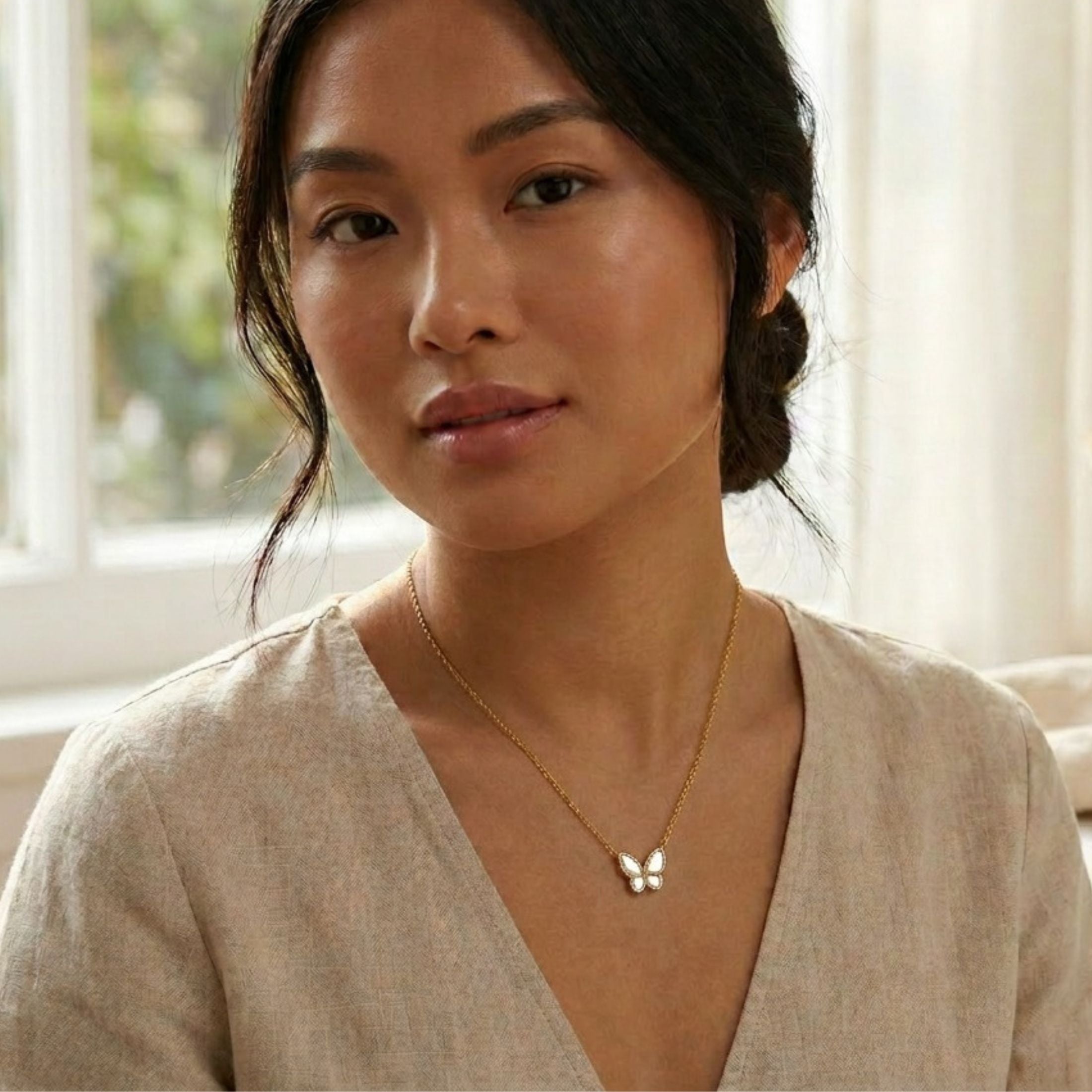 Woman wearing 18K yellow gold butterfly necklace with mother-of-pearl and diamonds