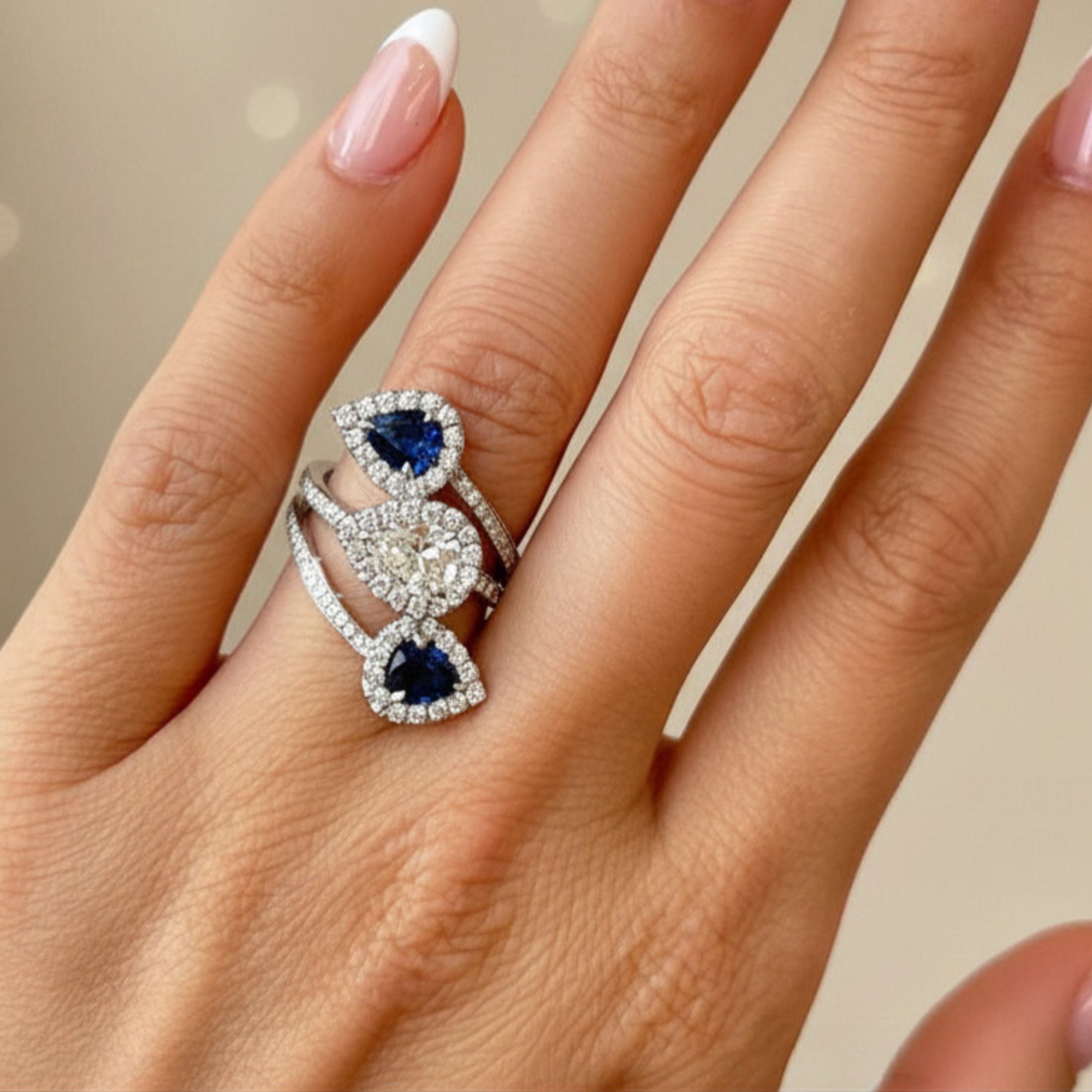 Leviev Reko bypass ring worn on right middle finger highlighting sculptural curve, royal blue sapphires, and pavé diamonds