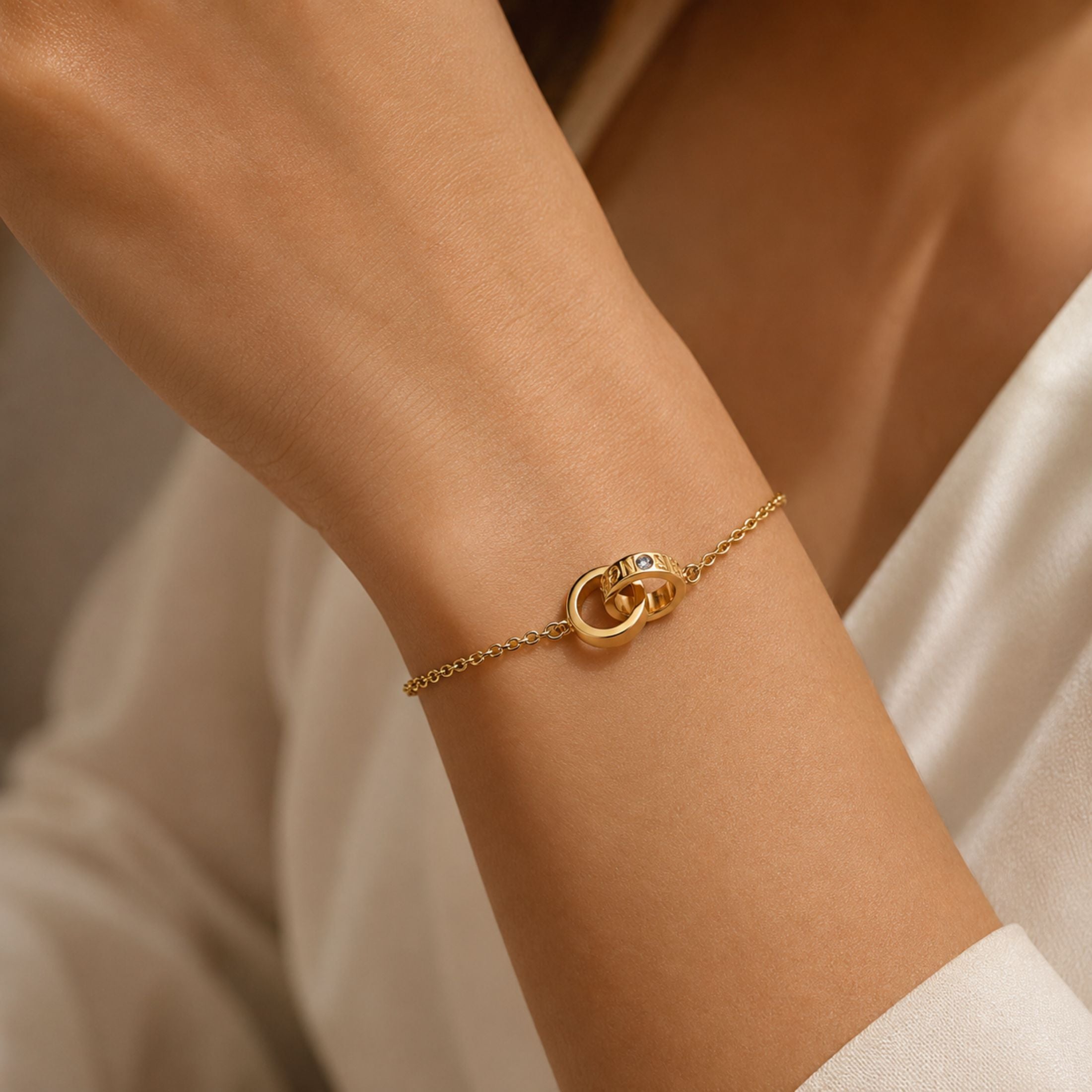 Yellow gold diamond charm bracelet worn on wrist showing fit and drape with interlocking rings and engraved 'STRONG' text
