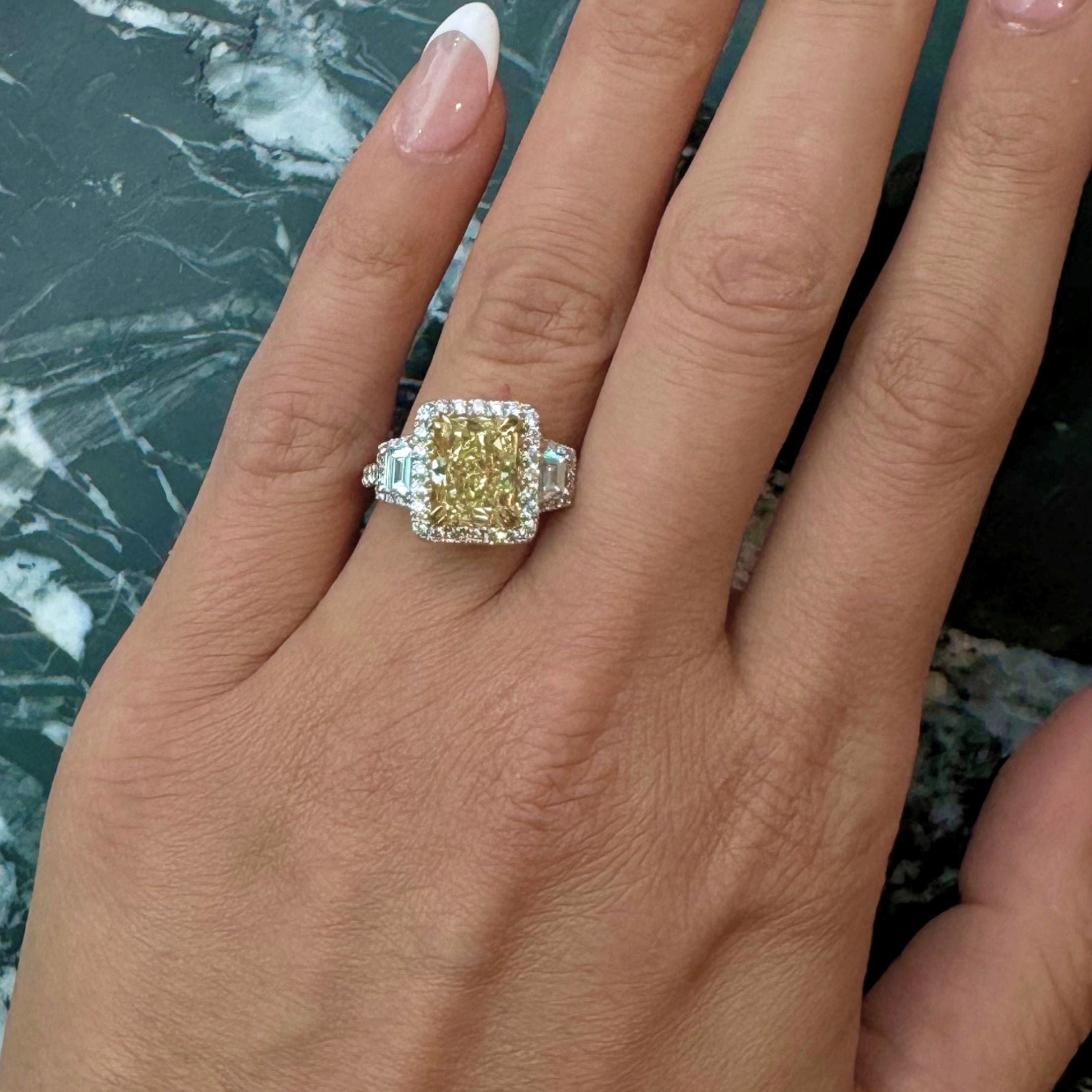 Woman wearing rectangular yellow diamond engagement ring on hand
