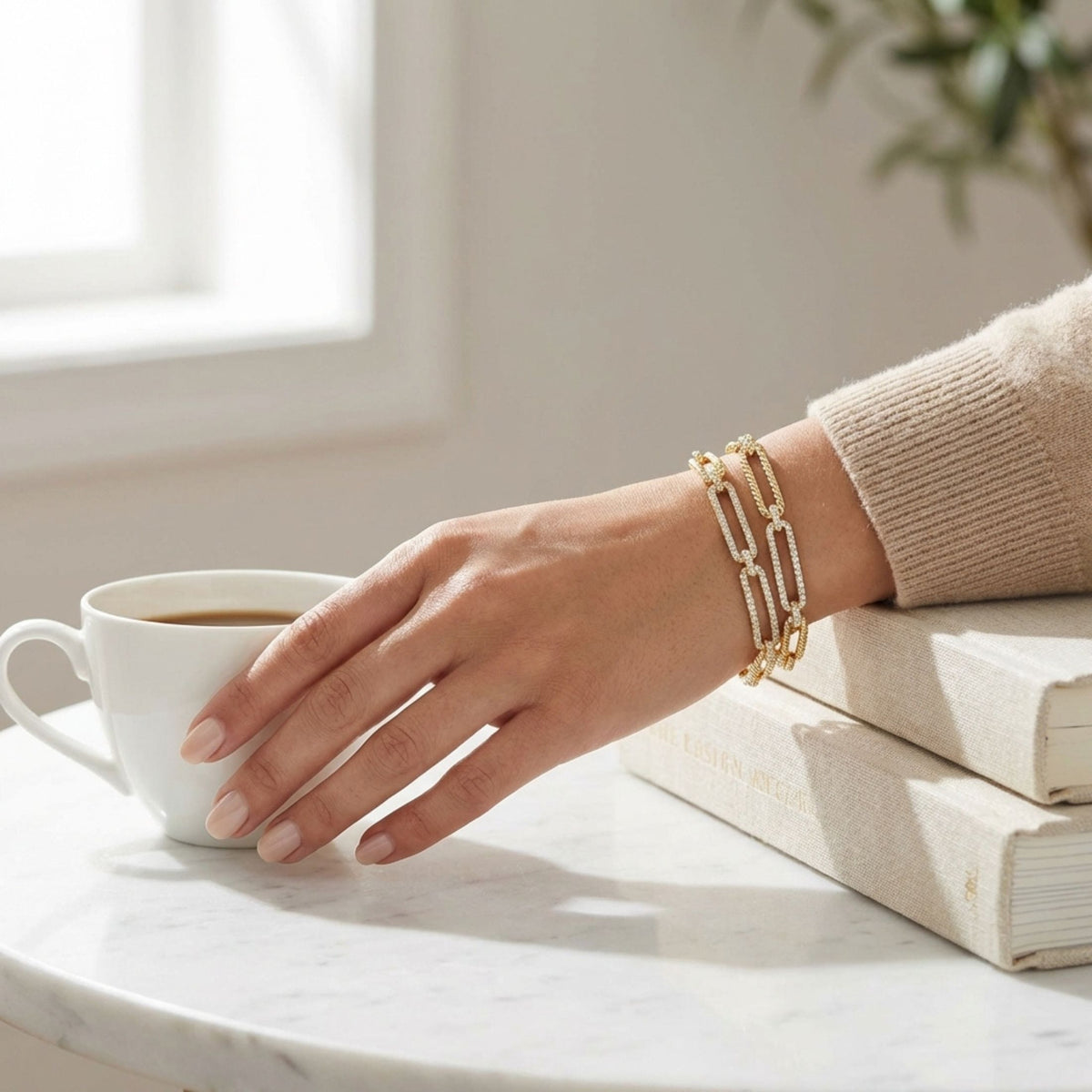 Everyday lifestyle shot of 14K yellow gold twisted link diamond bracelet styled with coffee cup and books