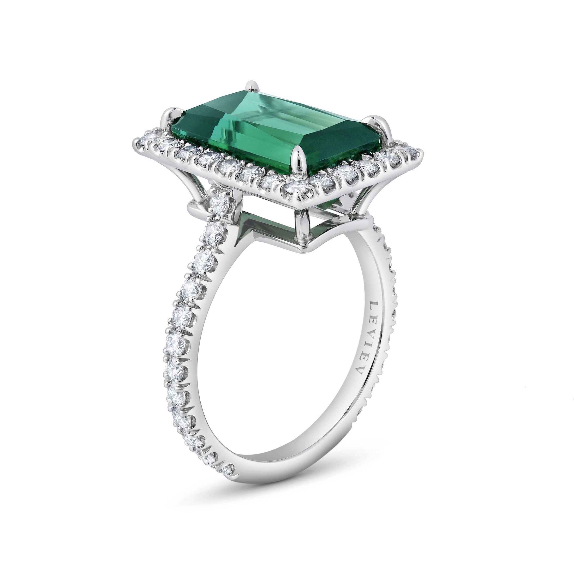Three-quarter view of engraved Leviev platinum band emerald cut green tourmaline diamond halo ring