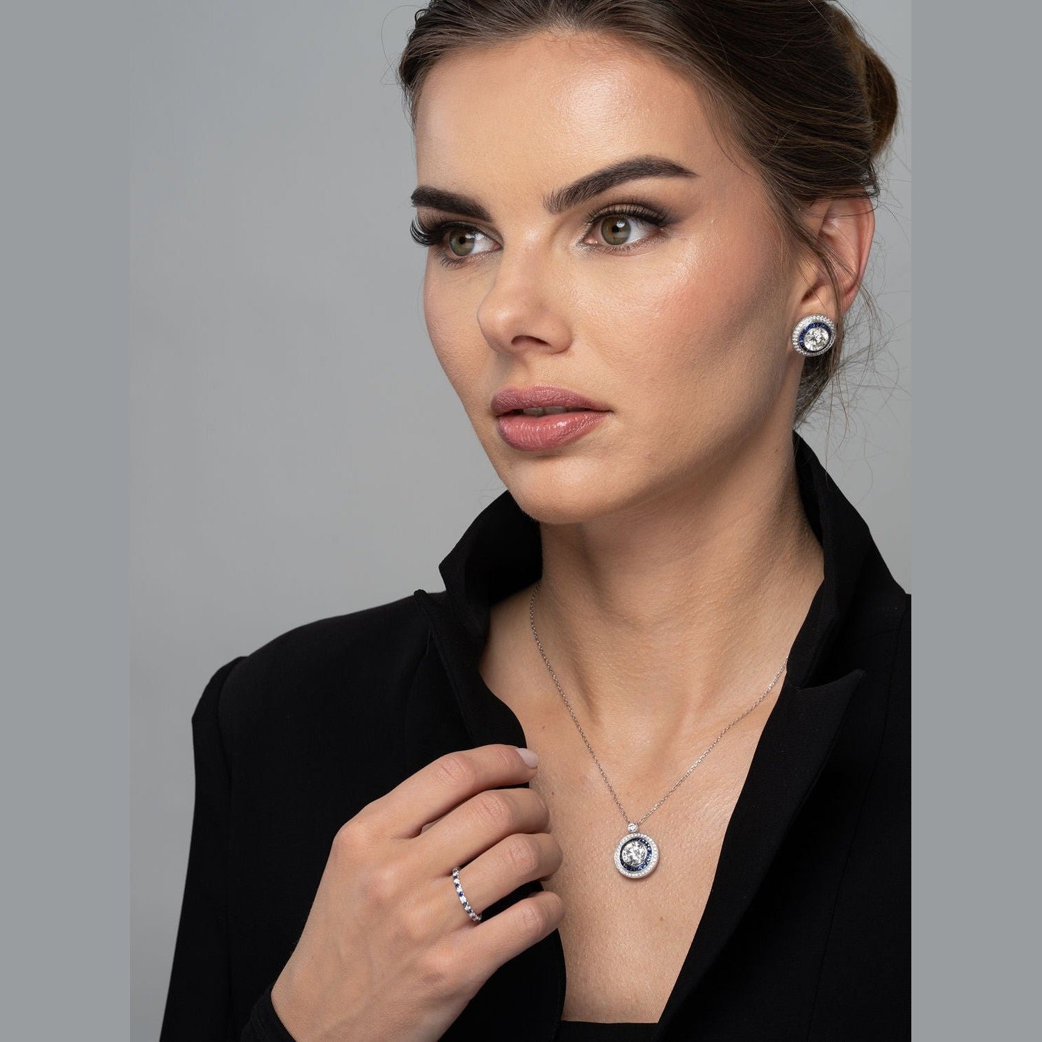 Woman wearing Leviev diamond sapphire pendant necklace with matching stud earrings and ring as coordinated jewelry set